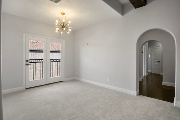 empty room with carpet and an inviting chandelier