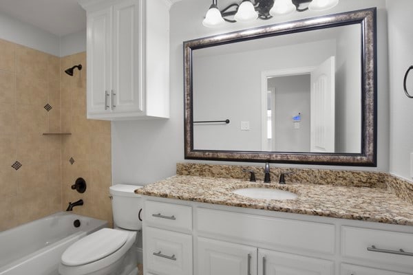 full bathroom featuring tiled shower / bath, vanity, and toilet