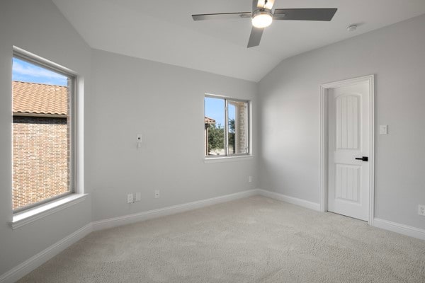 unfurnished room featuring light carpet, vaulted ceiling, and ceiling fan