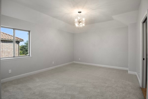 carpeted empty room with an inviting chandelier