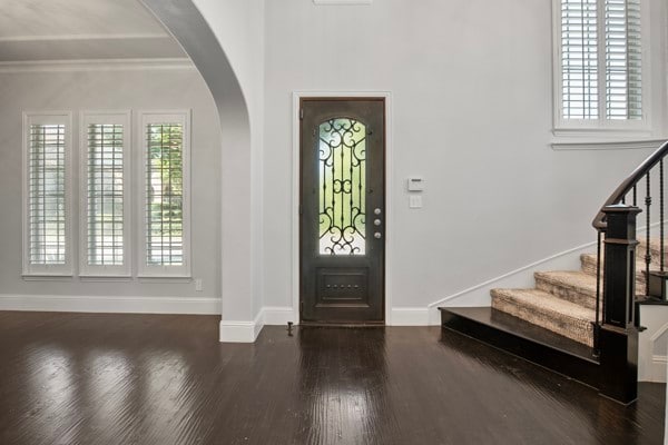 foyer entrance with crown molding and dark wood-type flooring