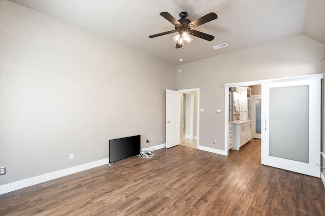 unfurnished bedroom featuring lofted ceiling, ensuite bathroom, wood-type flooring, and ceiling fan