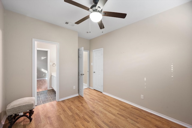 bedroom featuring connected bathroom, light wood-type flooring, and ceiling fan