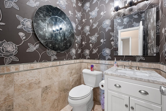 bathroom with toilet, vanity, and tile walls