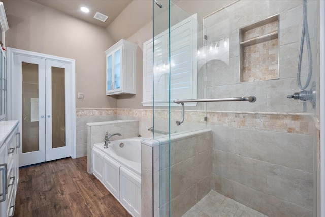 bathroom with vanity, tile walls, wood-type flooring, and plus walk in shower