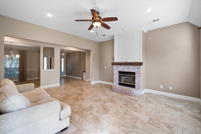 living room featuring ceiling fan with notable chandelier, vaulted ceiling, and a fireplace