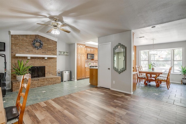 living room featuring hardwood / wood-style floors, lofted ceiling, ceiling fan, a fireplace, and a textured ceiling