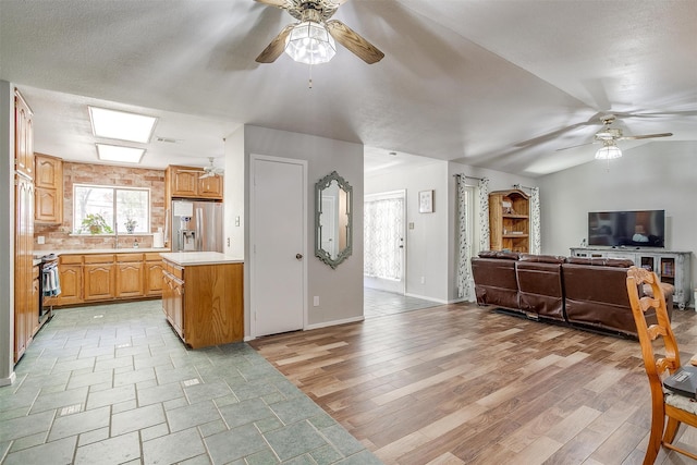 kitchen with ceiling fan, sink, lofted ceiling, appliances with stainless steel finishes, and light wood-type flooring