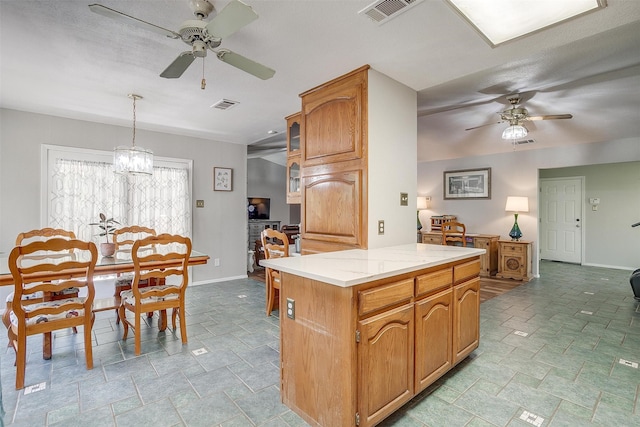 kitchen featuring a textured ceiling, a center island, hanging light fixtures, and ceiling fan with notable chandelier