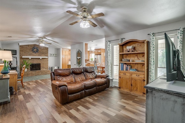 living room with a wealth of natural light, light hardwood / wood-style floors, and vaulted ceiling