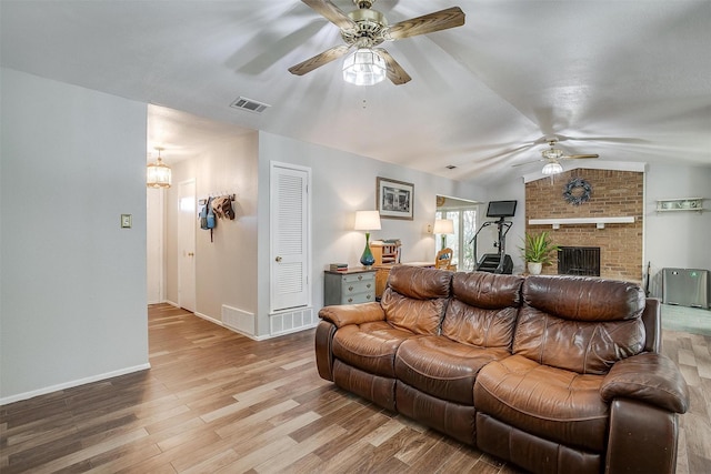 living room with light hardwood / wood-style floors, a brick fireplace, ceiling fan, and lofted ceiling