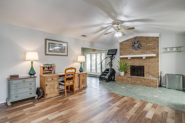 office space with a fireplace, light hardwood / wood-style floors, vaulted ceiling, and ceiling fan