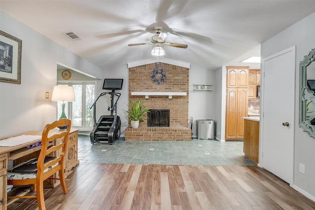 living room featuring a brick fireplace, ceiling fan, vaulted ceiling, and light wood-type flooring