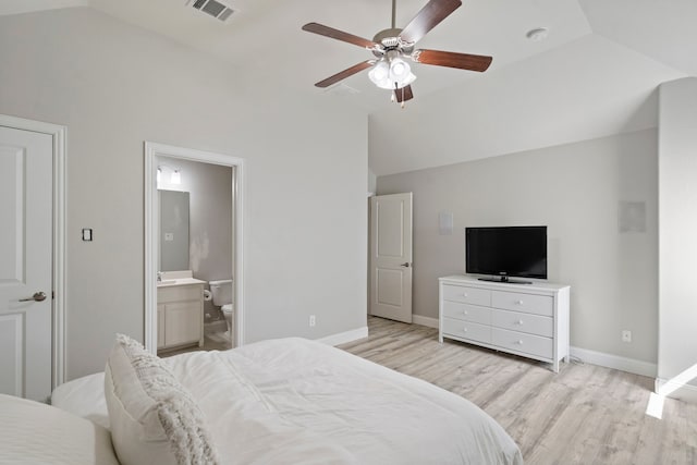 bedroom featuring light hardwood / wood-style floors, lofted ceiling, ensuite bath, and ceiling fan