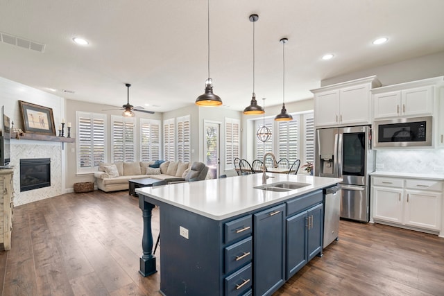 kitchen featuring blue cabinetry, stainless steel appliances, pendant lighting, and white cabinets