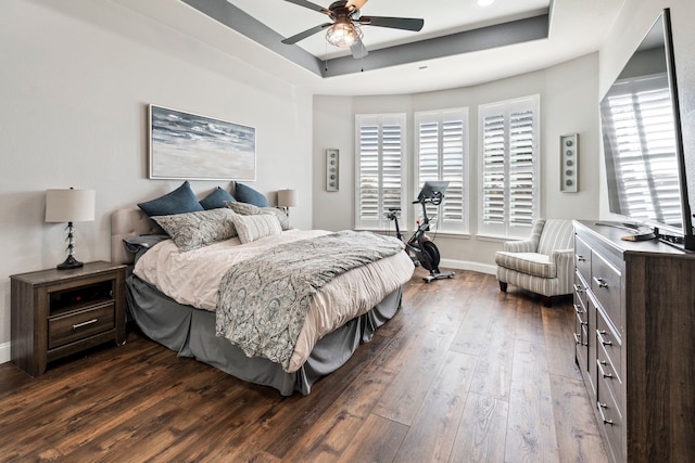 bedroom with ceiling fan, a tray ceiling, and dark hardwood / wood-style floors