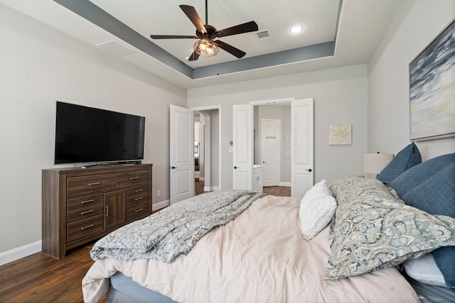 bedroom with ceiling fan, a tray ceiling, and dark hardwood / wood-style flooring