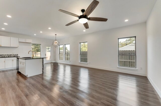 unfurnished living room with dark hardwood / wood-style floors, a healthy amount of sunlight, sink, and ceiling fan