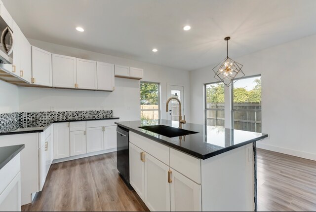 kitchen with black dishwasher, sink, plenty of natural light, and an island with sink