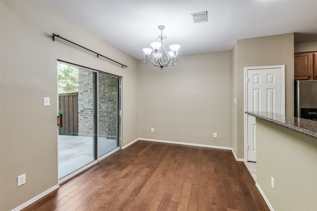 unfurnished dining area with hardwood / wood-style floors and an inviting chandelier