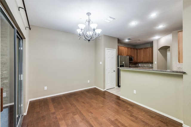 kitchen featuring appliances with stainless steel finishes, kitchen peninsula, a notable chandelier, and light wood-type flooring