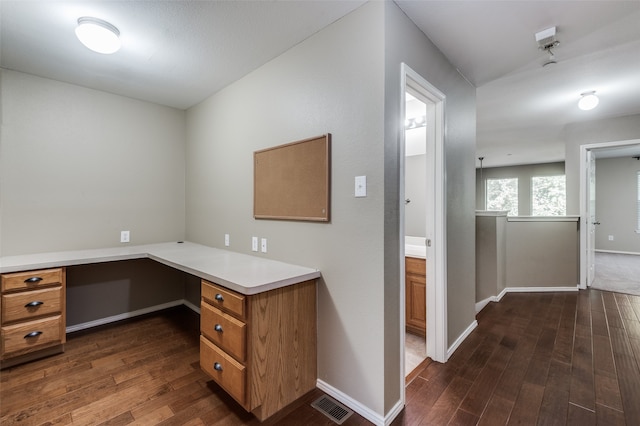 unfurnished office with built in desk and dark wood-type flooring