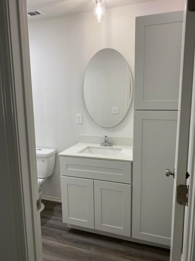 bathroom with toilet, hardwood / wood-style floors, and vanity