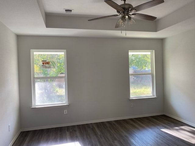 unfurnished room with a raised ceiling, ceiling fan, and dark hardwood / wood-style flooring