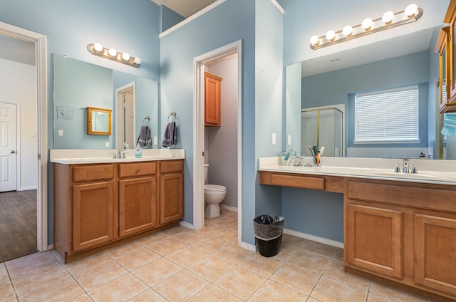 bathroom featuring a shower stall, toilet, two vanities, tile patterned floors, and a sink