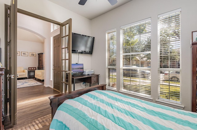 bedroom with a ceiling fan, wood finished floors, and arched walkways