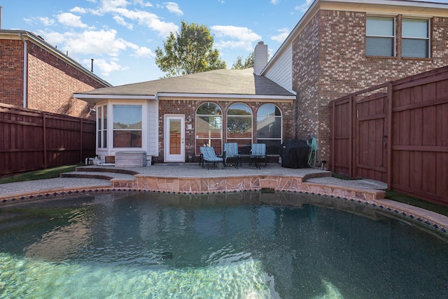 view of pool featuring a fenced in pool, a fenced backyard, a sunroom, a grill, and a patio