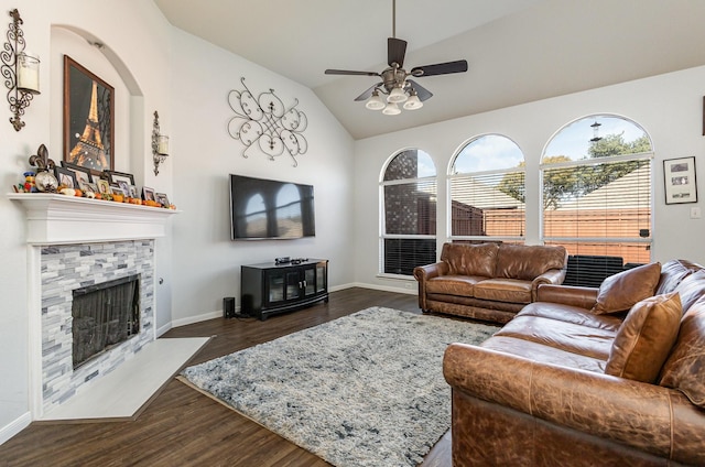 living room with dark hardwood / wood-style floors, vaulted ceiling, ceiling fan, and a stone fireplace