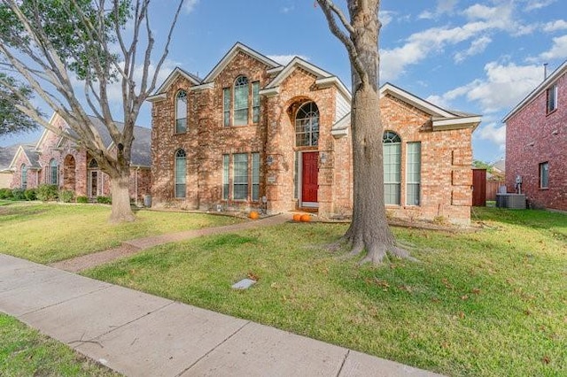 traditional home with brick siding, central AC, and a front lawn