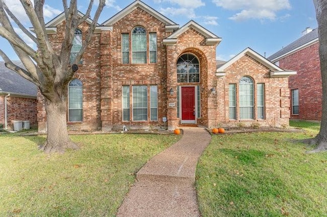 traditional-style home featuring brick siding and a front yard