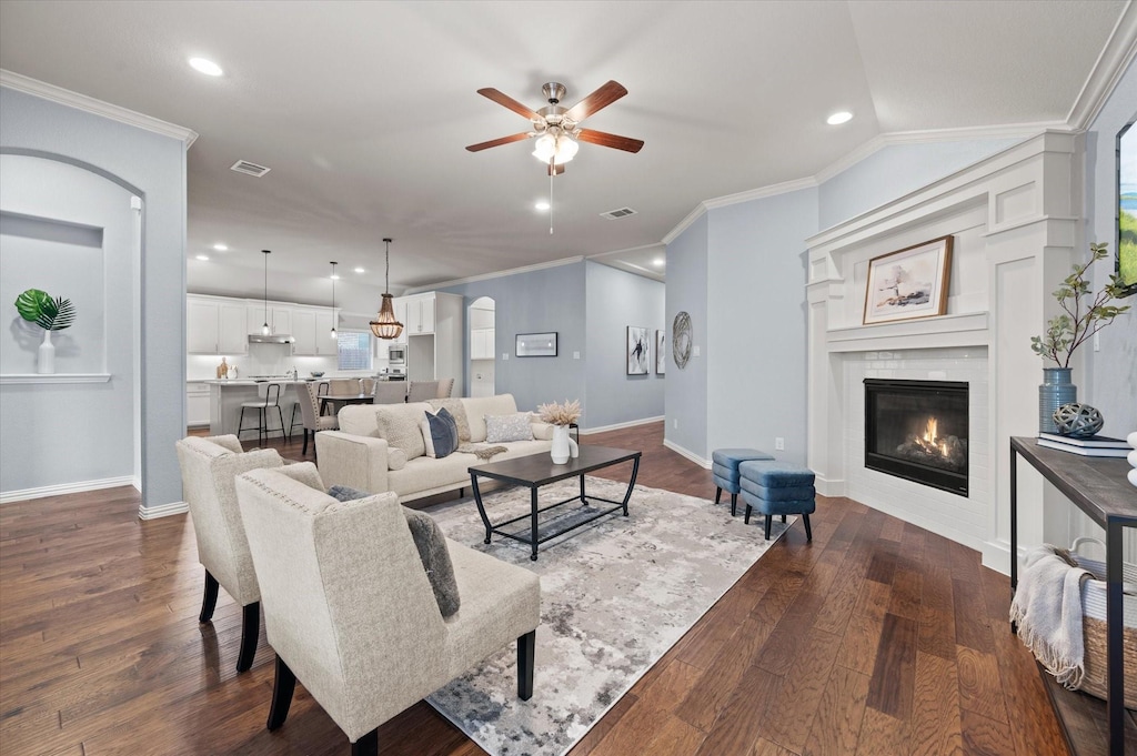 living room with ceiling fan, dark hardwood / wood-style flooring, crown molding, and vaulted ceiling