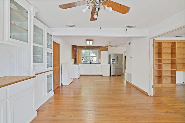 kitchen with stainless steel fridge, white cabinets, light hardwood / wood-style floors, and wood walls