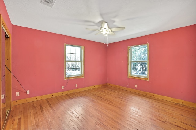 unfurnished room with light hardwood / wood-style flooring, a textured ceiling, a wealth of natural light, and ceiling fan