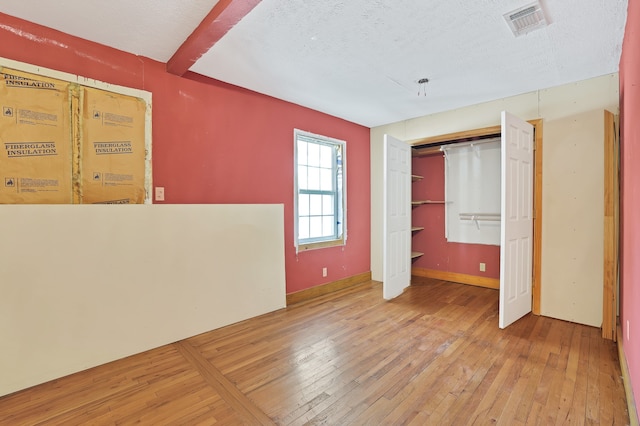 unfurnished bedroom with a closet, wood-type flooring, and a textured ceiling