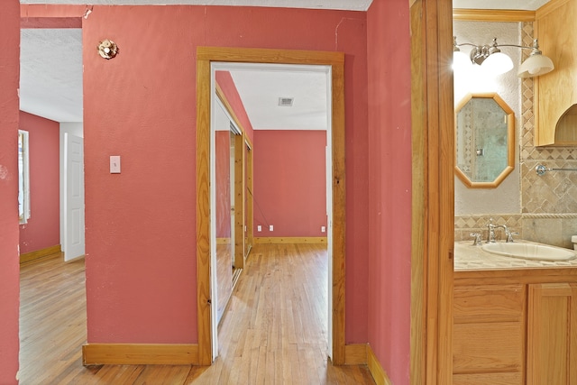 hallway featuring sink and light hardwood / wood-style floors