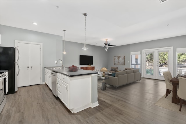 kitchen featuring wood-type flooring, sink, white cabinets, hanging light fixtures, and stainless steel appliances