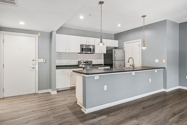 kitchen featuring appliances with stainless steel finishes, white cabinetry, hanging light fixtures, and sink