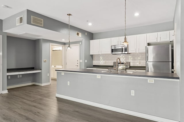 kitchen with pendant lighting, white cabinets, sink, appliances with stainless steel finishes, and tasteful backsplash