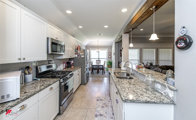 kitchen with sink, stainless steel appliances, pendant lighting, white cabinets, and ornamental molding