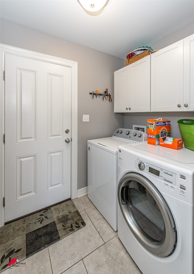 clothes washing area with light tile patterned floors, cabinets, and washing machine and clothes dryer