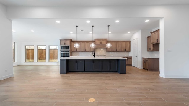 kitchen with appliances with stainless steel finishes, light wood-type flooring, light countertops, and backsplash