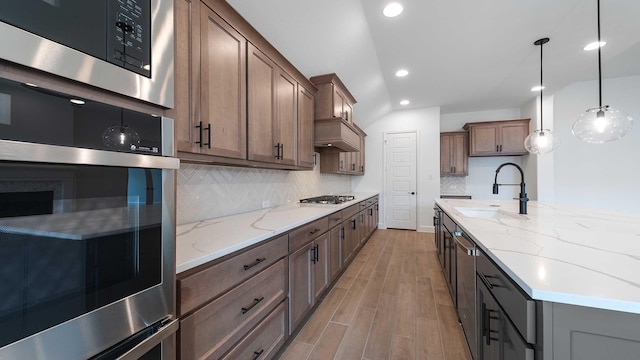 kitchen featuring light stone counters, recessed lighting, appliances with stainless steel finishes, light wood-style floors, and a sink