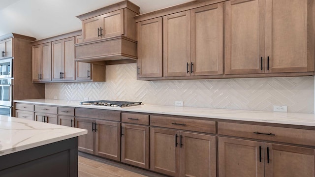 kitchen featuring stainless steel appliances, light stone counters, and decorative backsplash