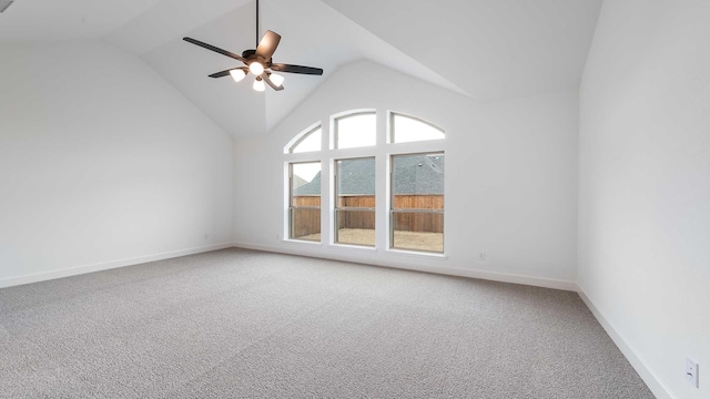 spare room with light carpet, ceiling fan, vaulted ceiling, and baseboards