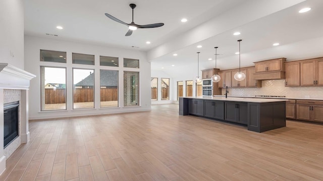 kitchen featuring stainless steel microwave, open floor plan, light countertops, a fireplace, and backsplash