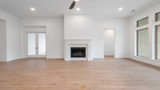 unfurnished living room featuring light wood-type flooring, french doors, a fireplace, and recessed lighting